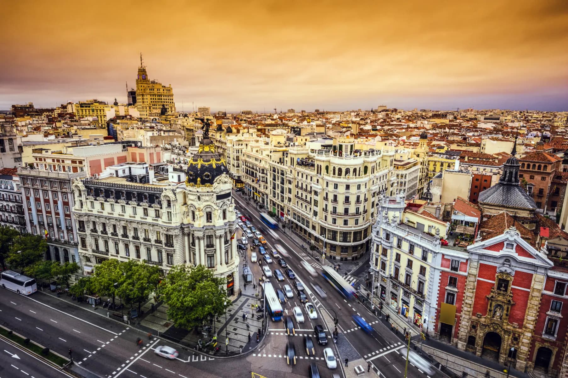 Aerial view of Madrid's Gran Via at golden hour, with classical architecture and modern energy meeting